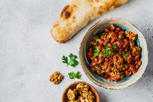 Georgian cozy winter lobio with red beans, walnuts and herbs served in a rustic bowl with fresh bread on a light stone background